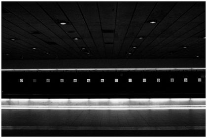 A theatres check room. The ceiling lines run into the image in a center perspective, ending in horizontal lines. The central part has number labels corresponding to wardrobe numbers.