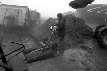A young man using a machine to mix fertilizer in a pit