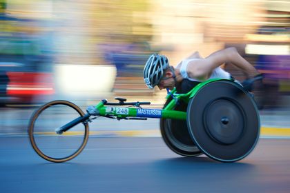 Man in a racing wheelchair going so fast the background blurs